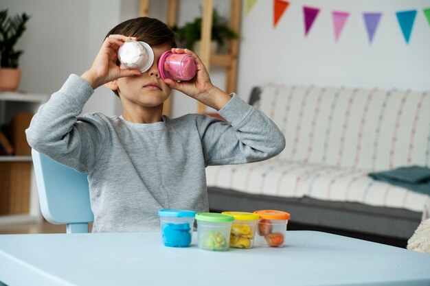 Medium shot kid holding playdough containers