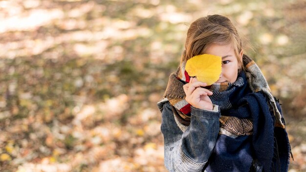 黄色の葉を持っているミディアムショットの子供