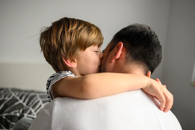 Bambino del colpo medio che abbraccia suo padre