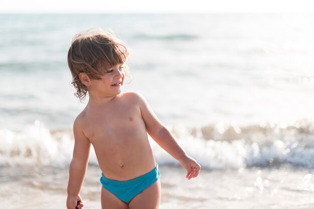 Средний снимок ребенка, смотрящего на пляж