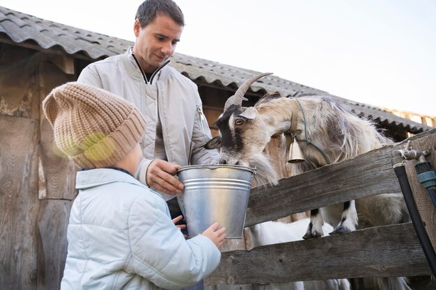 Medium shot kid and man feeding goat