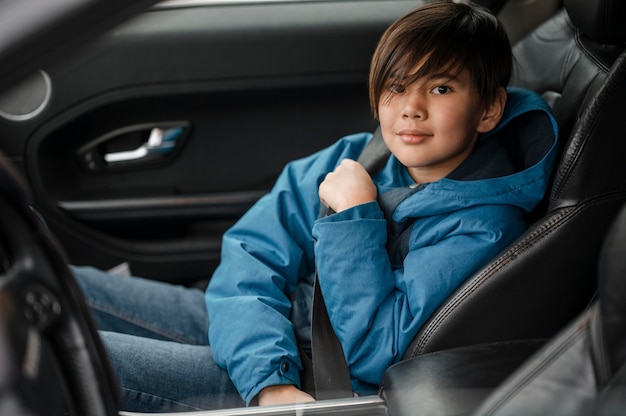 Free photo medium shot kid sitting in car