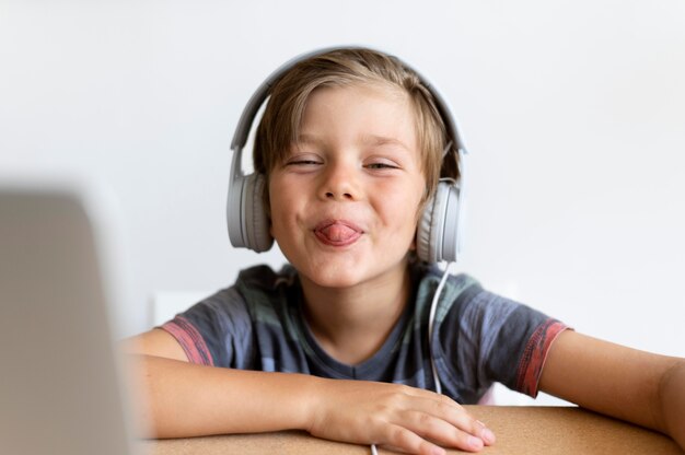 Medium shot kid sitting at desk with headphones