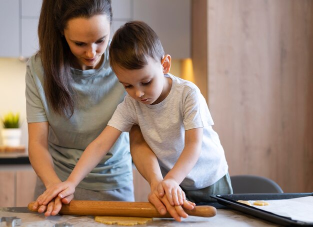 Medium shot kid and woman using rolling pin