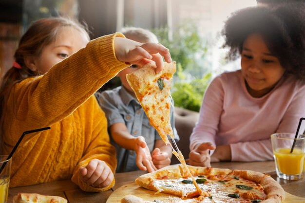 Medium shot kids eating pizza