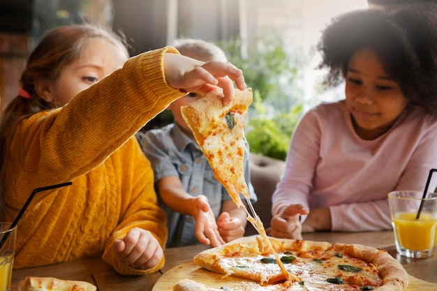 Дети среднего размера, едящие пиццу