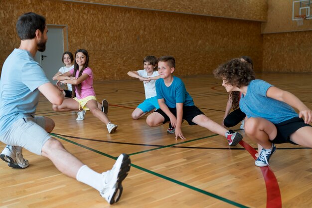 Bambini di tiro medio che si esercitano nella palestra della scuola