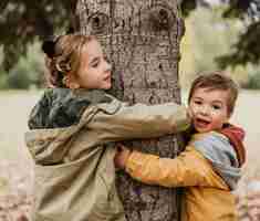 Free photo medium shot kids hugging tree