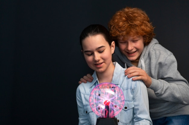 Foto gratuita bambini di tiro medio che interagiscono con una palla al plasma