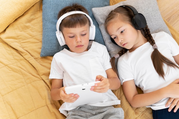 Free photo medium shot kids laying with devices