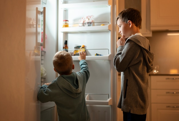 Medium shot kids looking in the fridge