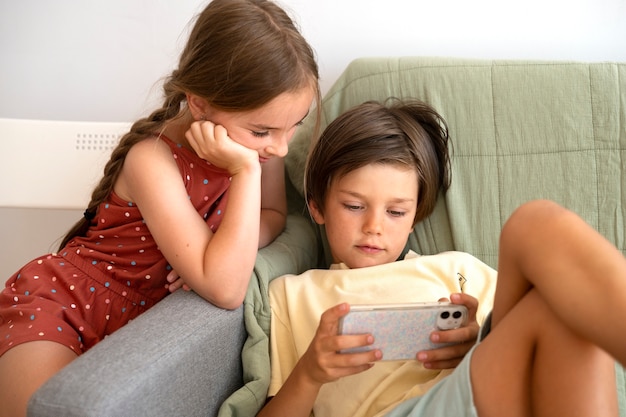 Дети среднего кадра, смотрящие на смартфон