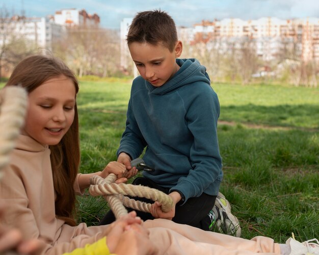 Medium shot kids playing tug-of-war in the park