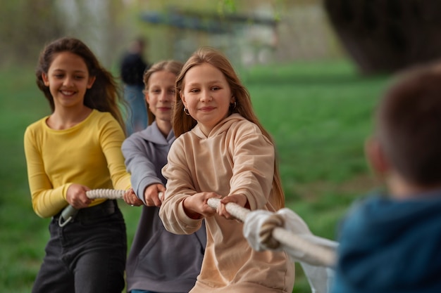 Medium shot kids playing tug-of-war in the park