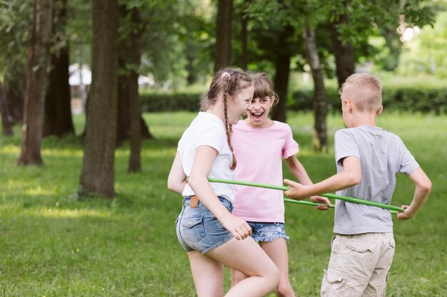 Medium shot kids playing with hula hoop together