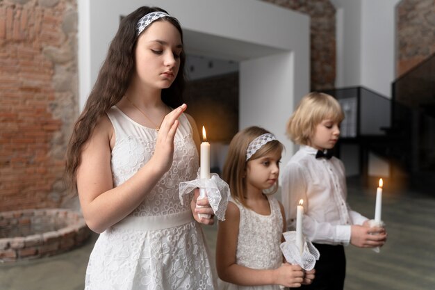 Дети среднего плана молятся со свечами