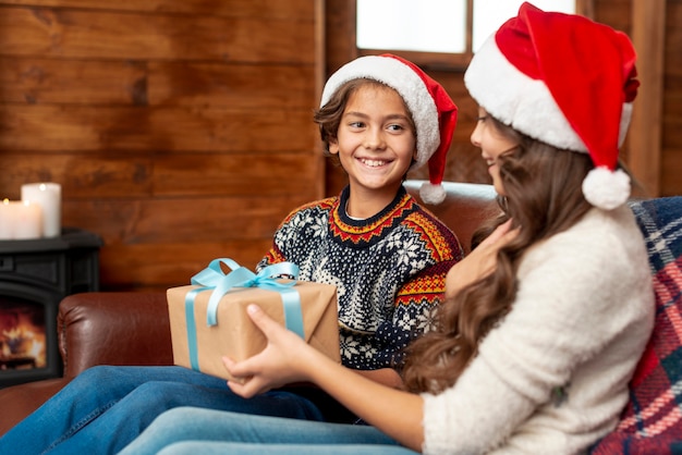 Medium shot kids sitting on the couch with gift