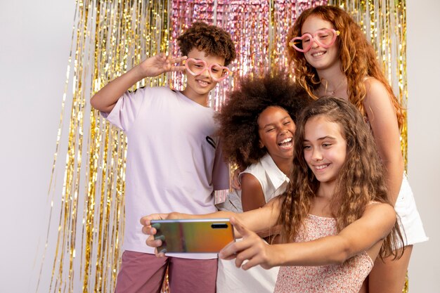 Medium shot kids taking selfie at party