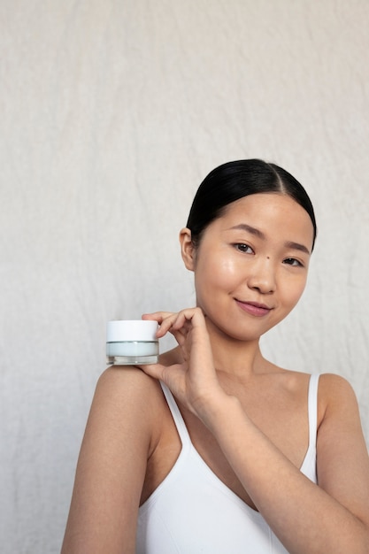 Free photo medium shot korean woman posing with face cream