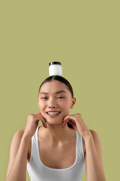 Free photo medium shot korean woman posing with face cream