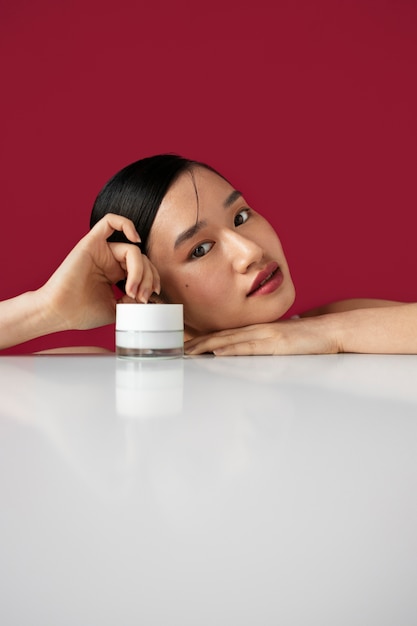 Free photo medium shot korean woman posing with face cream