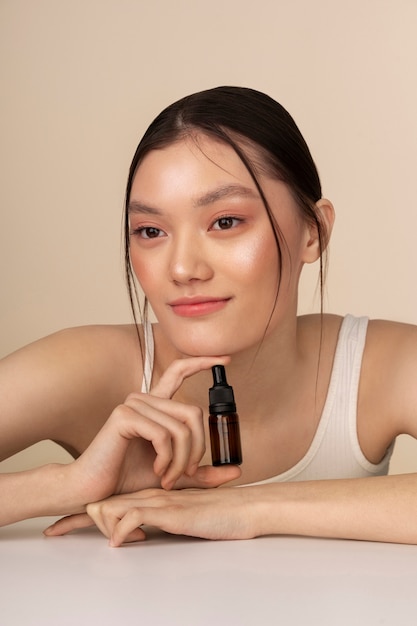 Free photo medium shot korean woman posing with serum bottle