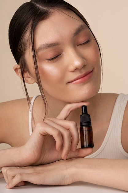 Free photo medium shot korean woman posing with serum bottle