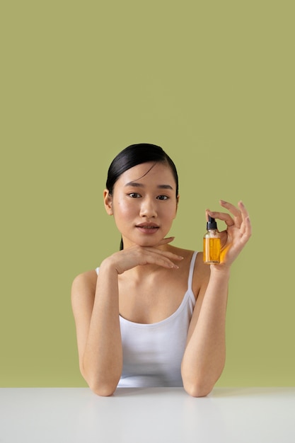 Free photo medium shot korean woman posing with serum