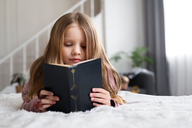 Бесплатное фото Маленькая девочка среднего роста читает библию