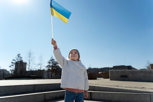 medium shot little kid holding ukrainian flag