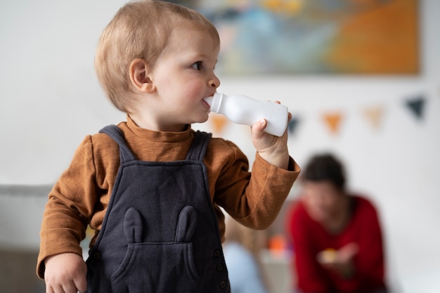 Medium shot little kid with baby bottle