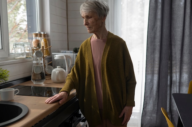 Бесплатное фото Одинокая пожилая женщина среднего выстрела на кухне