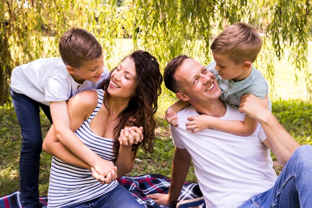 Free photo medium shot lovely family playing on picnic blanket