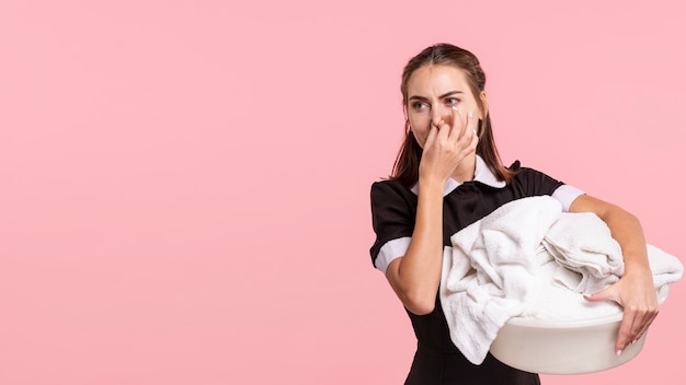 Medium shot maid holding a smelly laundry basket 