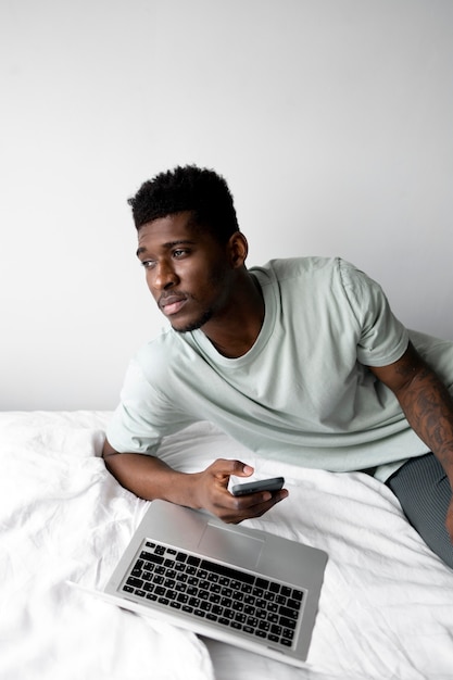 Medium shot man in bed with devices