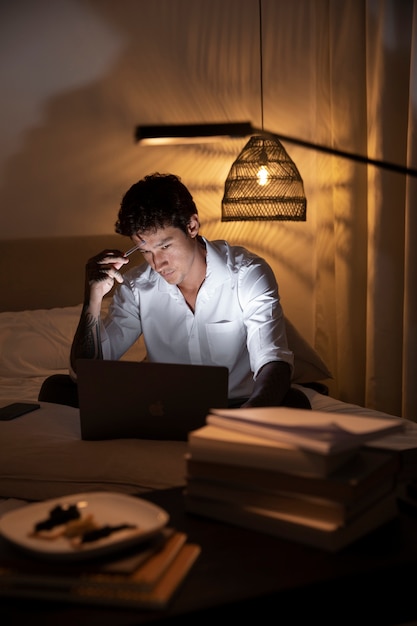 Medium shot man in bed with laptop