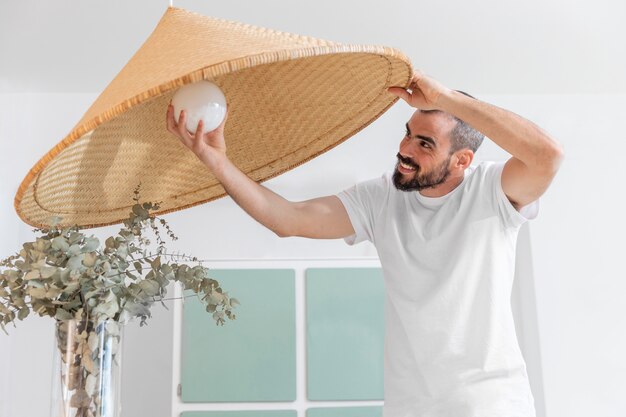 Medium shot man changing light bulb