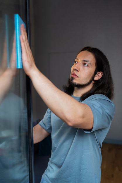 Medium shot man cleaning window