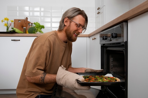 Foto gratuita uomo del colpo medio che cucina pizza