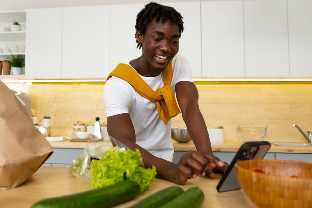 Medium shot man cooking with smartphone