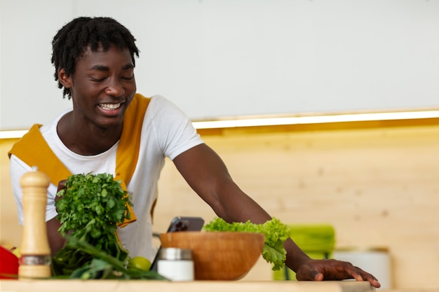 Foto gratuita uomo di tiro medio che cucina con lo smartphone