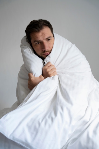 Free photo medium shot man covering himself with blanket