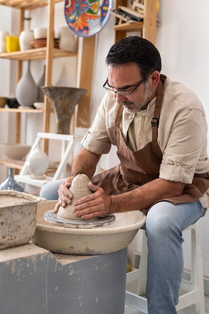 Medium shot man doing pottery indoors