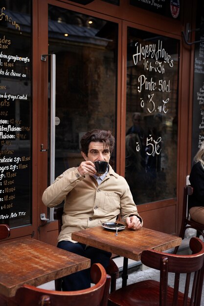 Medium shot man drinking coffee at bistro