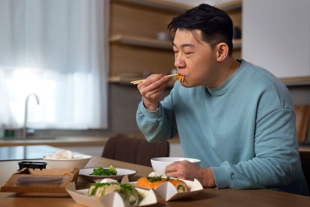 Medium shot man eating asian food