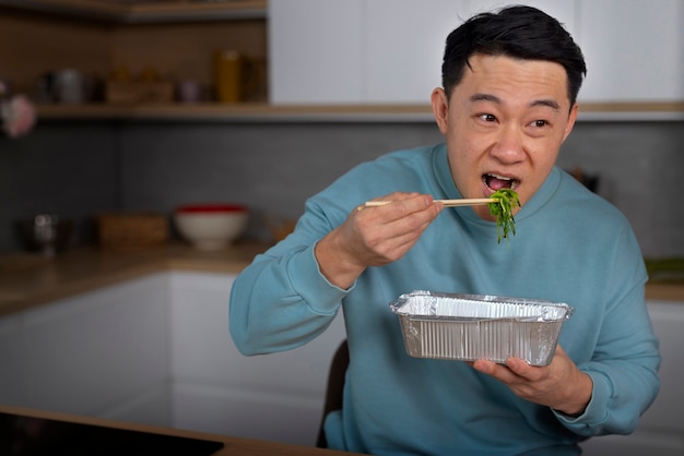 Free photo medium shot man eating asian food