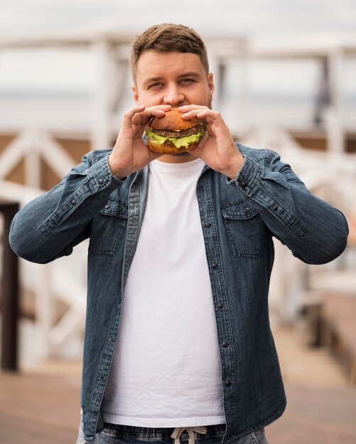 ハンバーガーを食べるミディアムショットの男