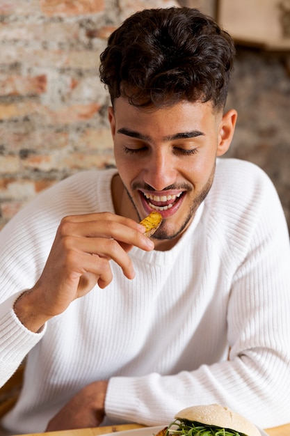 Foto gratuita uomo che mangia patata del colpo medio