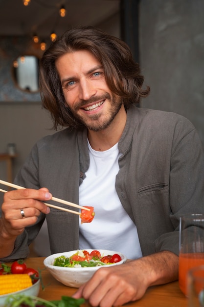 Free photo medium shot man eating salmon bowl