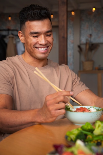 Medium shot man eating salmon bowl